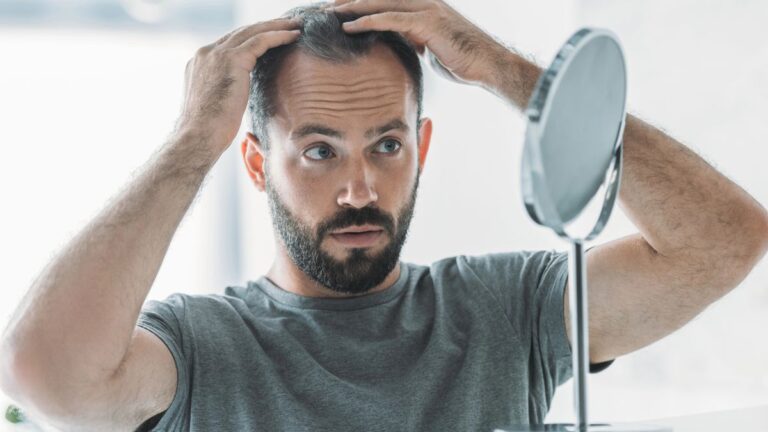 man looking at hair in the mirror