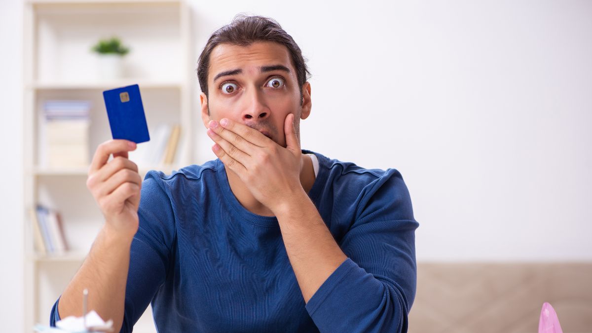 man looking surprised with credit card and computer