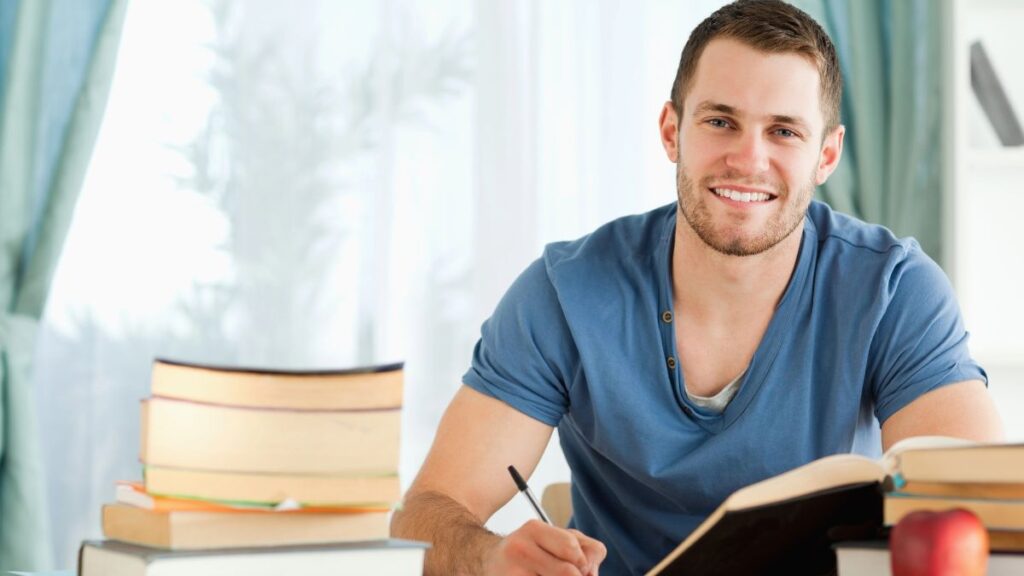 man writing with books