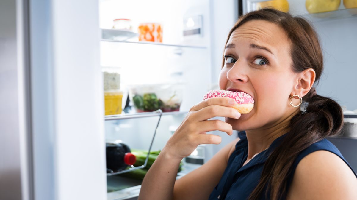 stressed woman eating donut in fridge