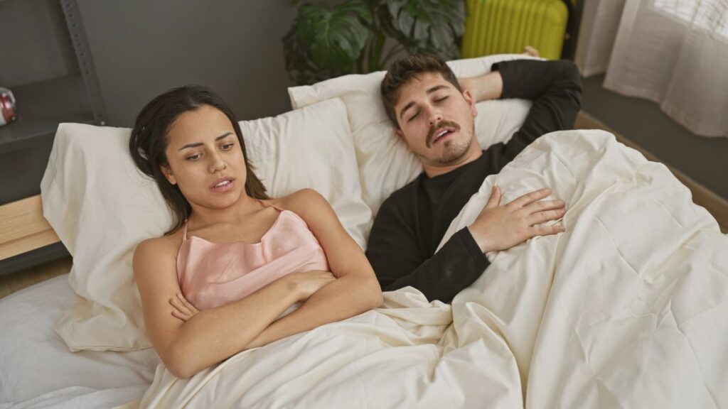 unhappy woman in bed with man sleeping