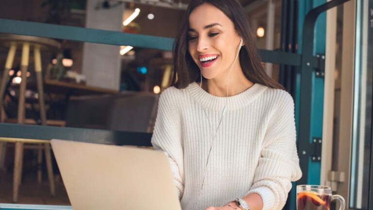 woman in white smiling at computer