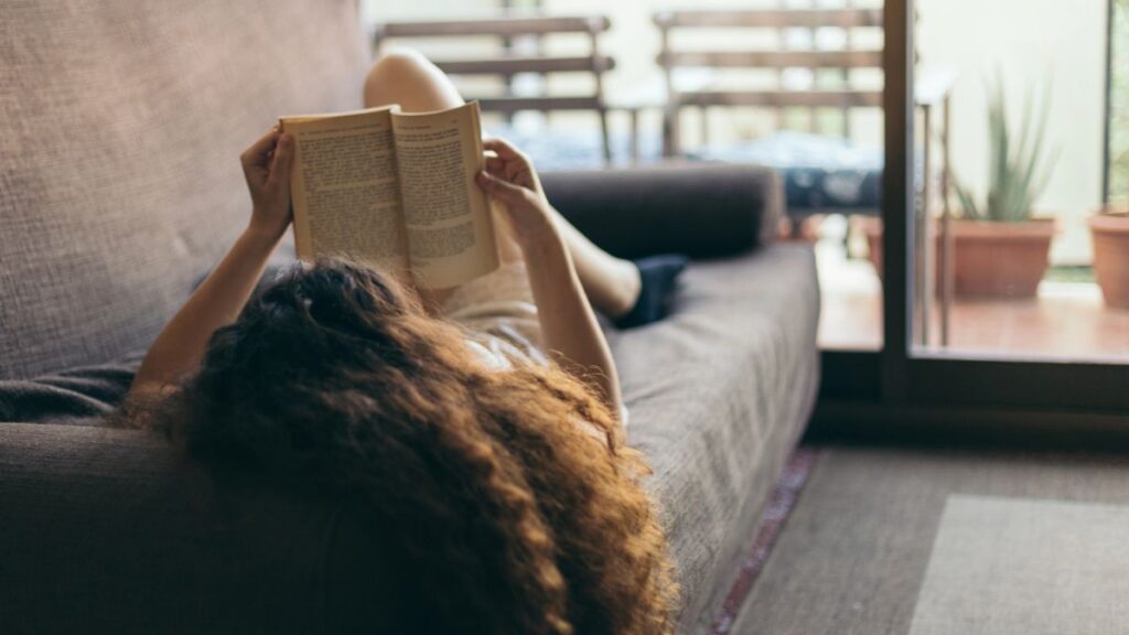 woman laying on couch reading