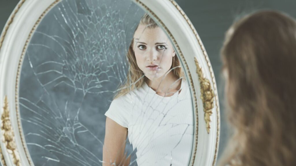 woman looking at broken mirror