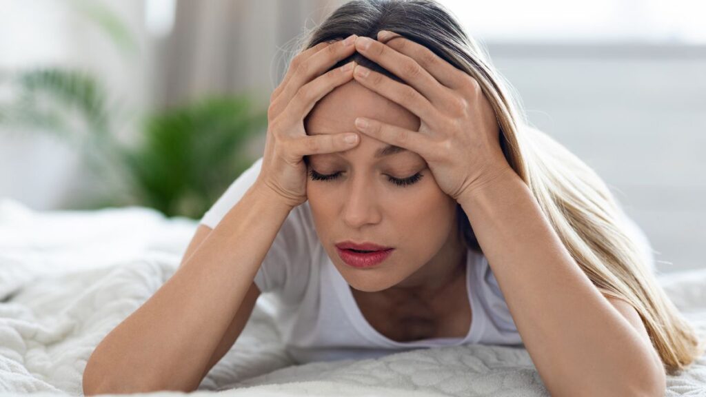 woman on bed with headache