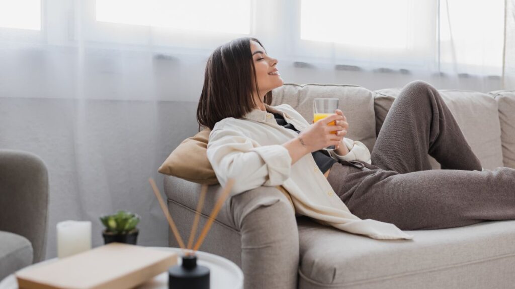 woman relaxing on couch with orange juice