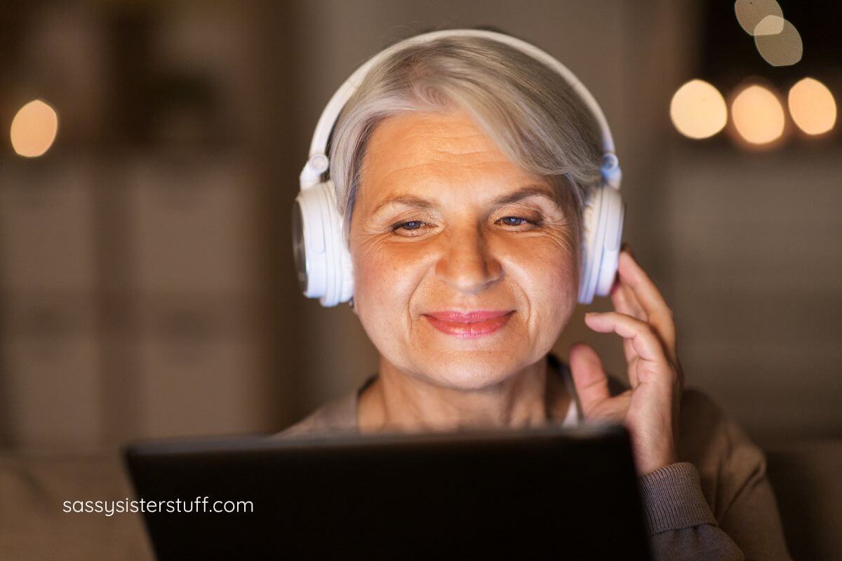 middle aged woman with noise reduction headphones on as she listens to a book.