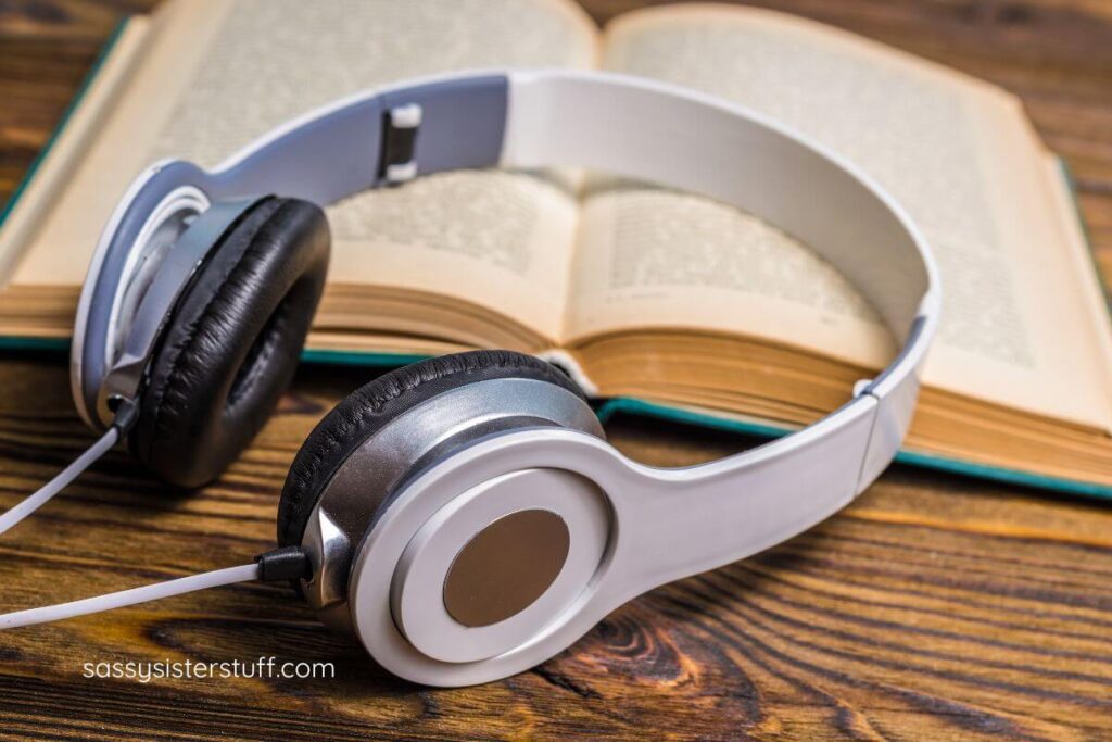 close-up top view of headphones and an open book laying on a desk.