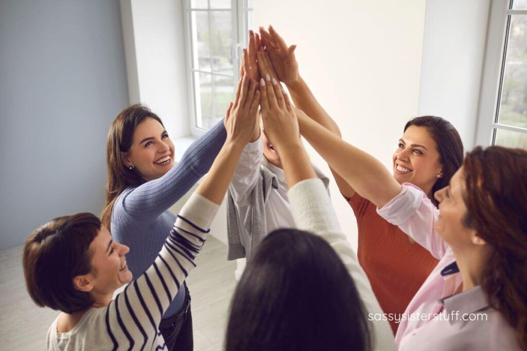 a group of women do a high five to celebrate empowering words for women and girls.