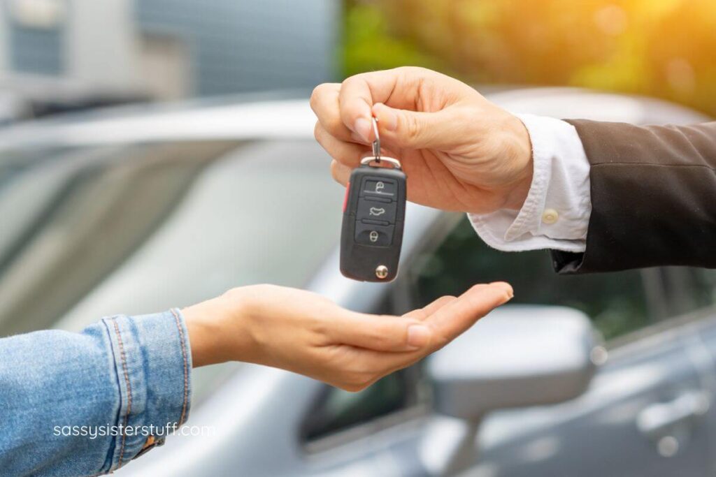 close-up of a car salesman handing car keys to a female buyer.