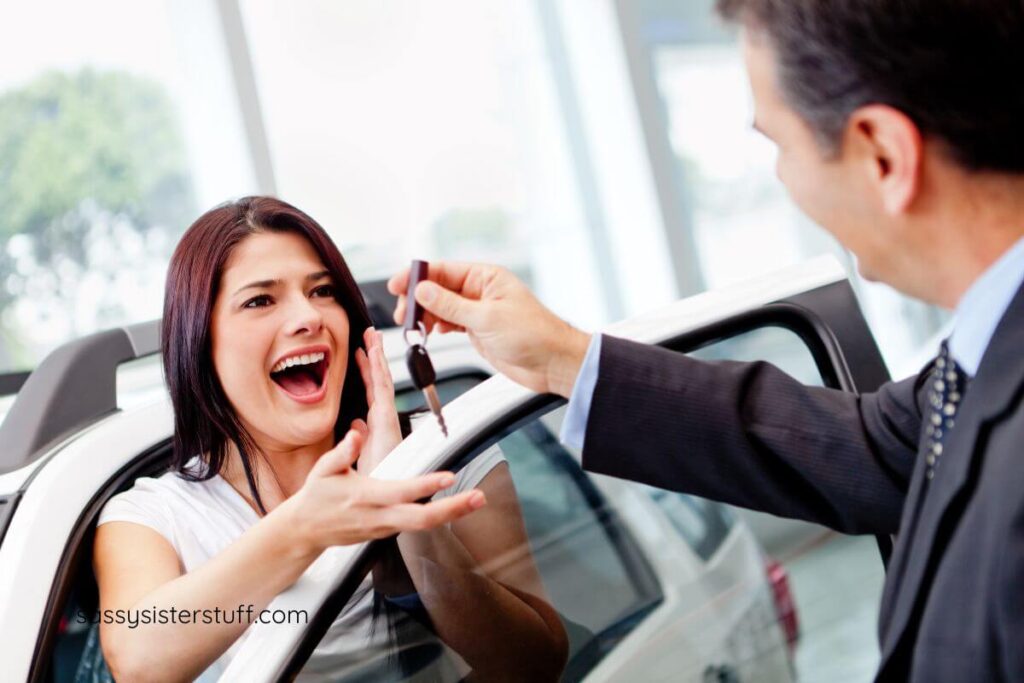 excited woman accepts keys from a salesman after buying a car.