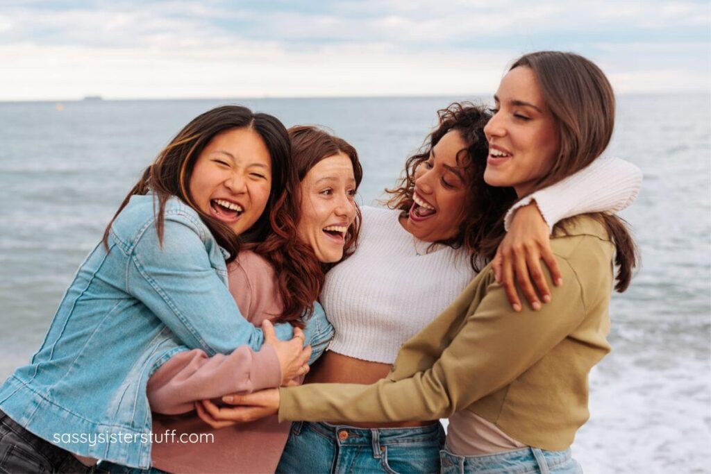 four women of various ages hug each other and laugh together.