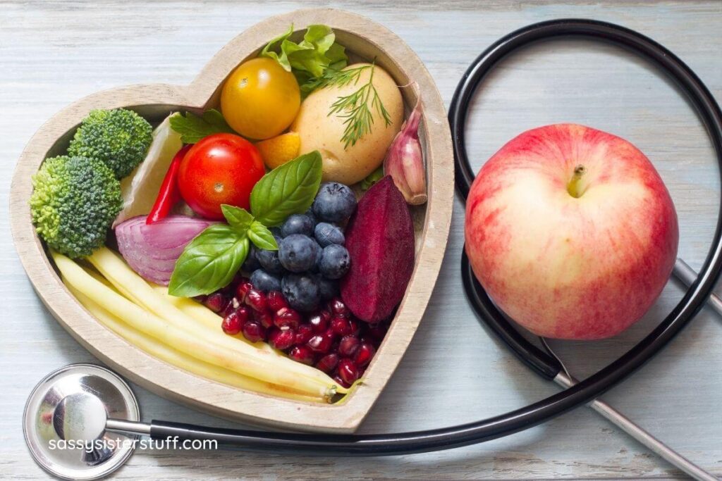 to view of heart shaped bowl filled with fruit and stethoscope on table.