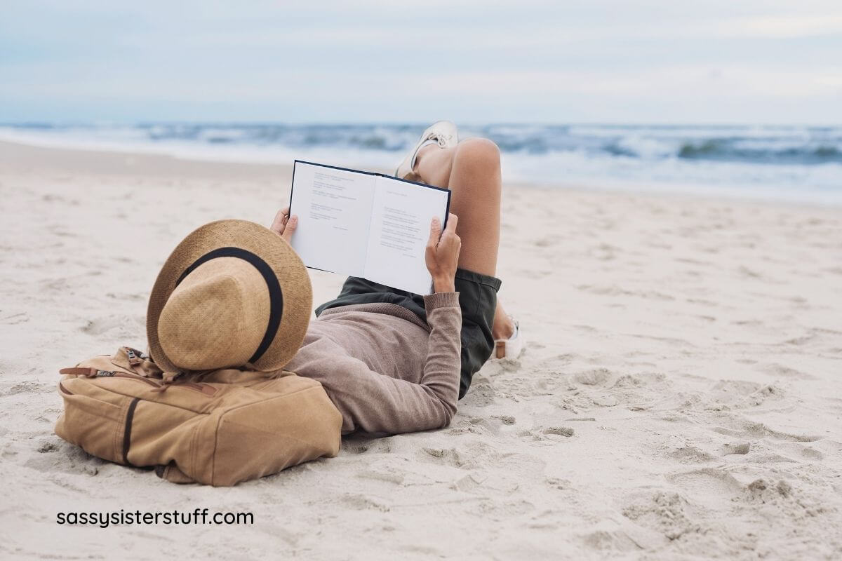 woman laying on beach reading a book about how to unlock your best self.