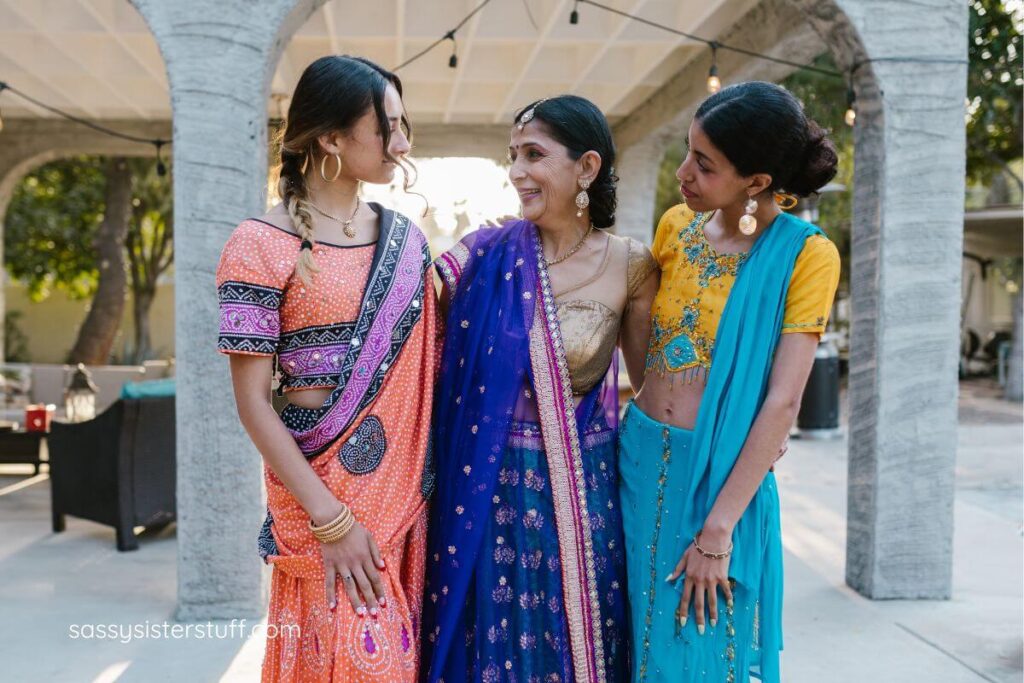 3 beautiful Indian women embrace lovingly.