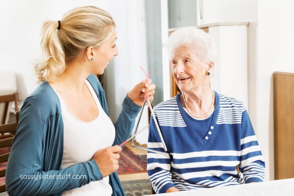 adult woman and senior woman with dementia play with a musical triangle.