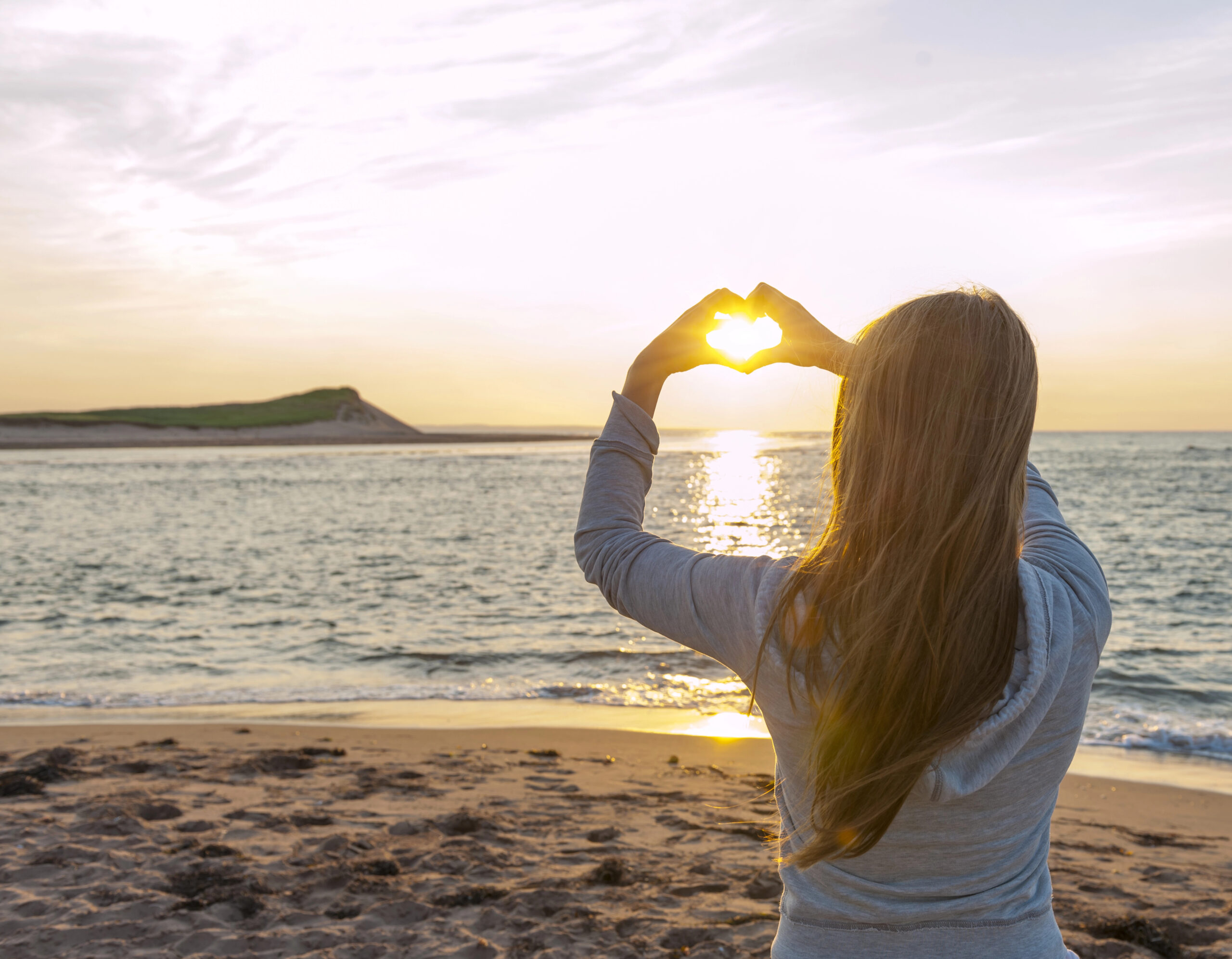 woman watching sunset with hands in heart