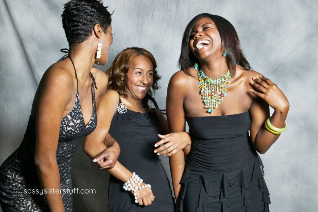 three women embrace each other and laugh together after learning the 10 benefits of social interaction.