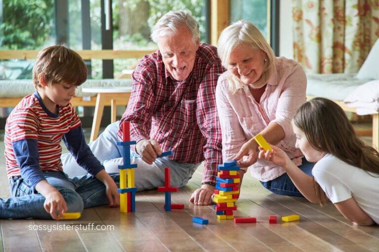 grandparents play a floor game with blocks with their two grandchildren.