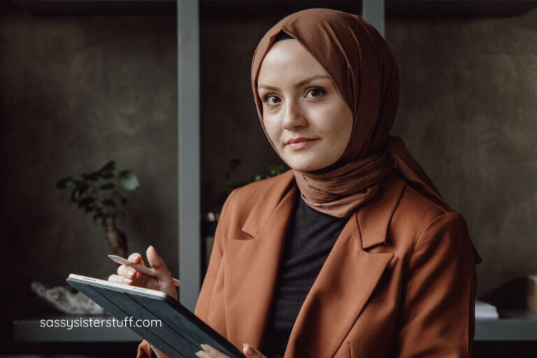 women with a scarf on her head in a business suit, working on a tablet.