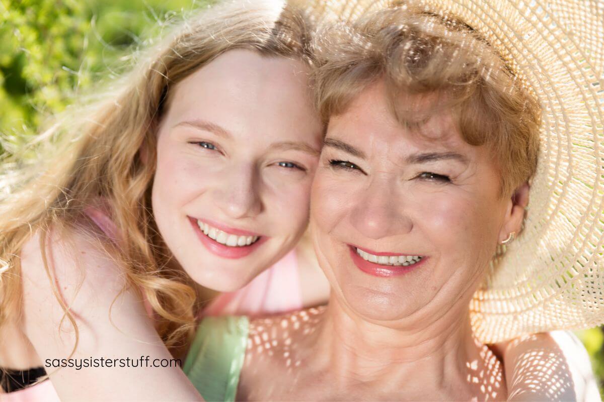 adult granddaughter poses check to check with her grandmother and they both smile.