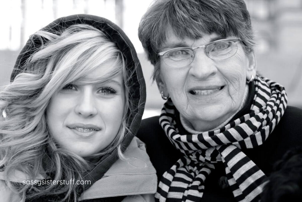 black and white close-up of adult granddaughter and grandmother standing close together in the cold.