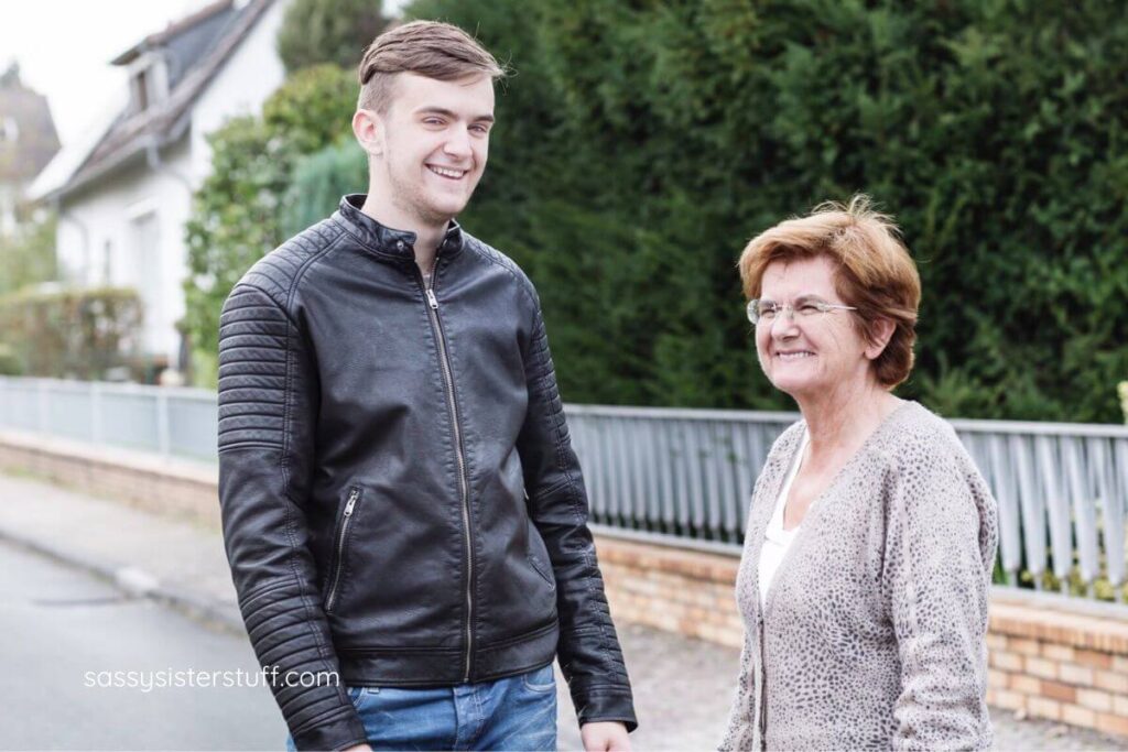 grandmother and adult grandson stand on the street together.