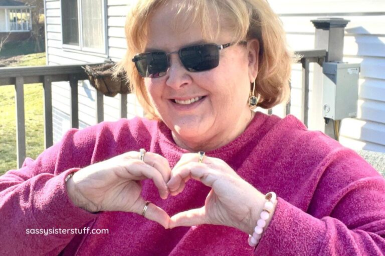 happy middle aged woman making a heart with her hands after reading love yourself poems and quotes.