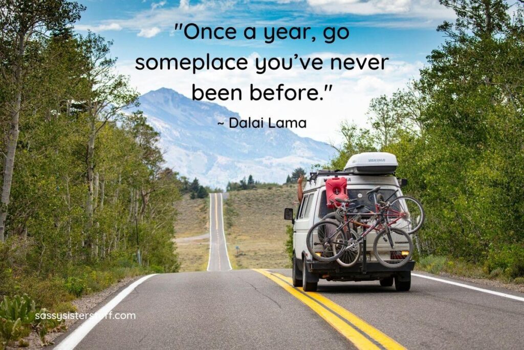 travel camper driving through the mountains; Quote: Once a year, go someplace you've never been before. - Dalai Lama