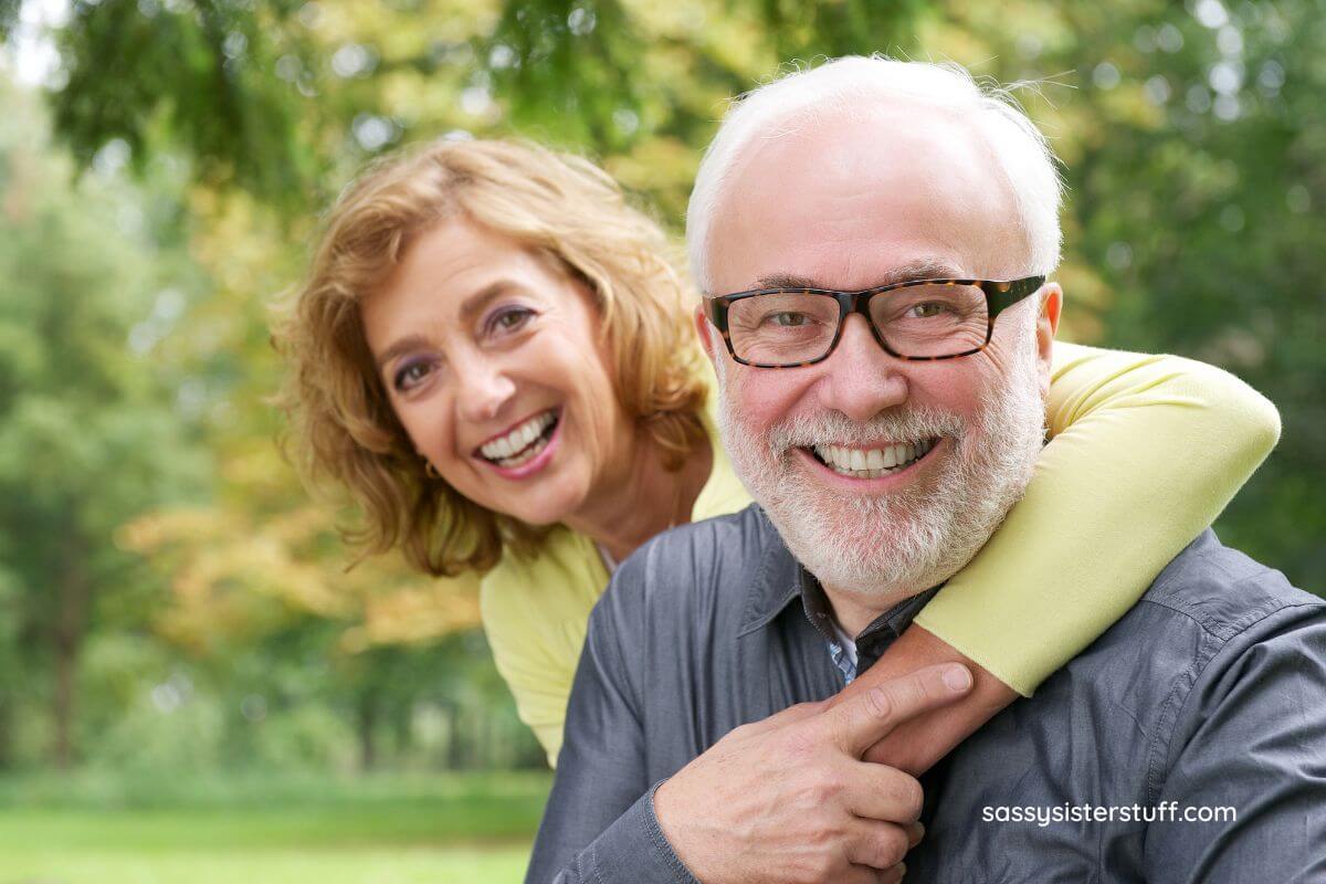 older couple in a park on a sunny day smiling for the camera.