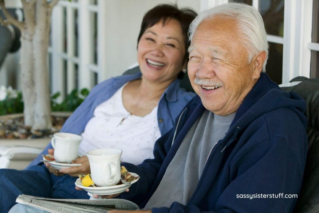 older couple having coffee together outside and laughing together.