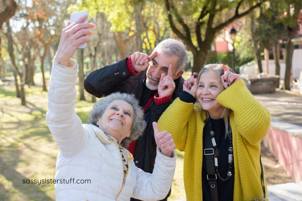 group of three elderly people making silly faces and smiling for a selfie.