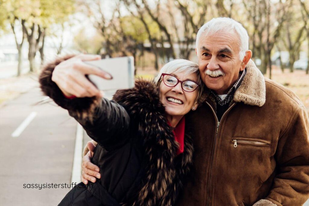 an older couple in a park take a selfie together showing their nice smiles.