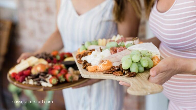 two ladies showing healthy charcuterie lunch boards that they made for a girlfriends luncheon.