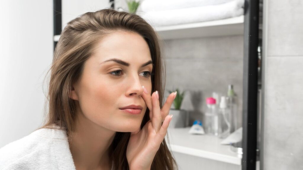 woman looking at face in mirror