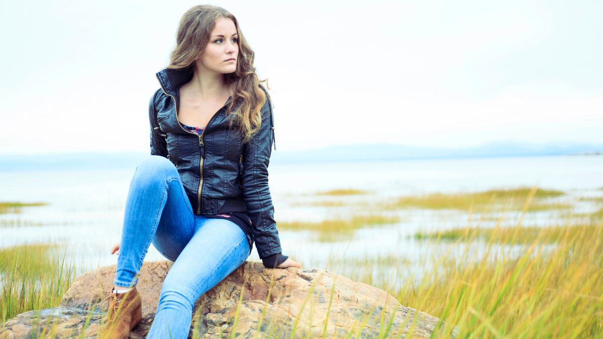 woman sitting outside by water looking stressed