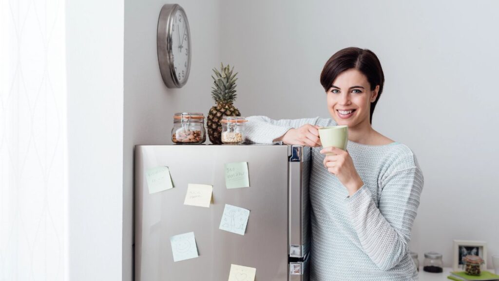 woman standing at fridge with coffee