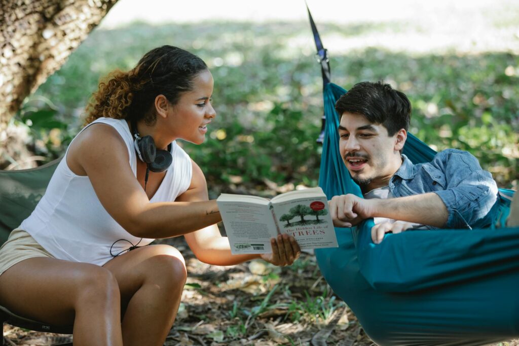 A happy couple enjoying a book and each other's company in a hammock outdoors.